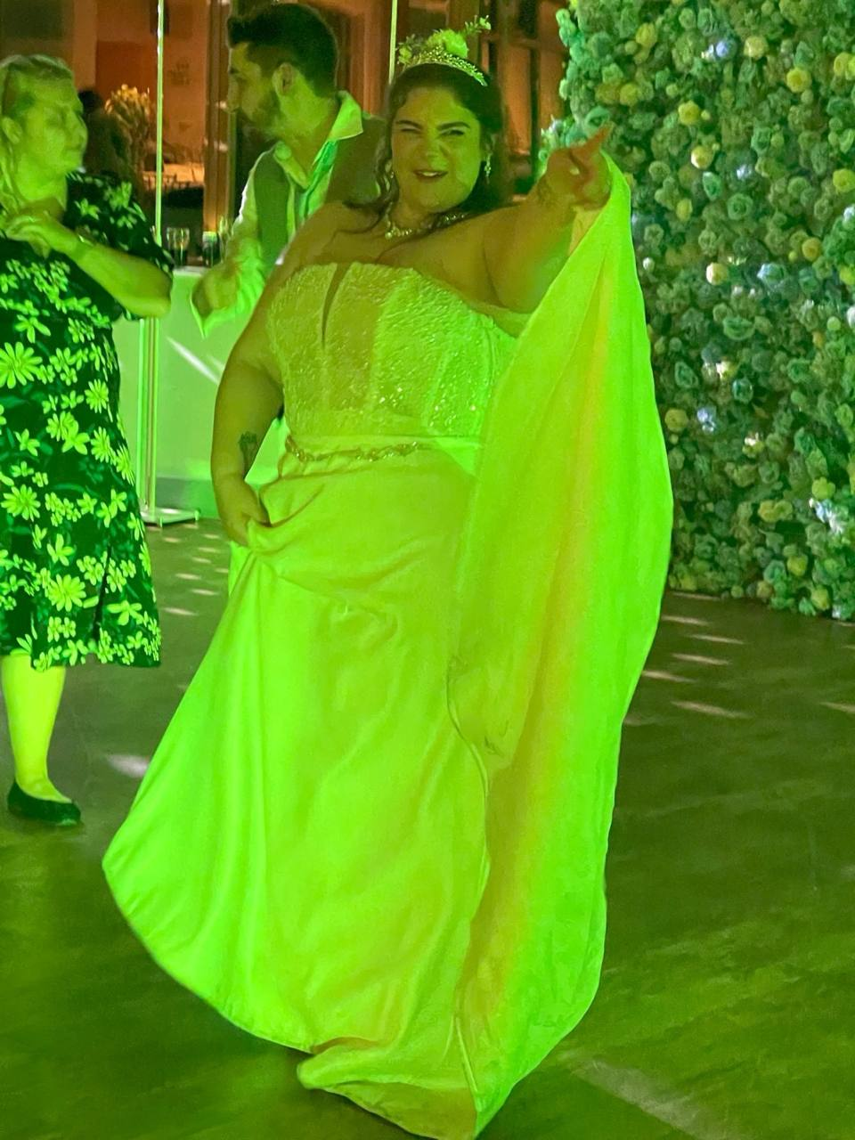 A bride smiling and pointing towards the DJ on the wedding dance floor
