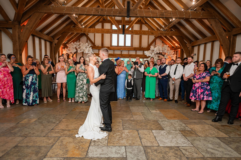 A couple enjoying their first dance with their guests gathered around them